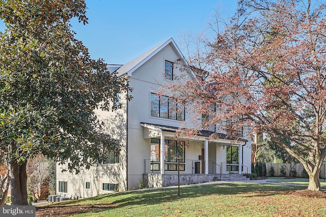 view of front facade featuring stucco siding, fence, a porch, and a front yard