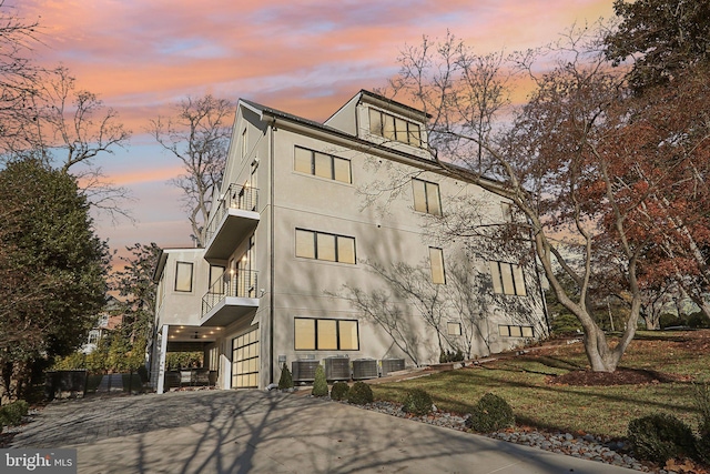 property at dusk featuring driveway, a garage, and central AC