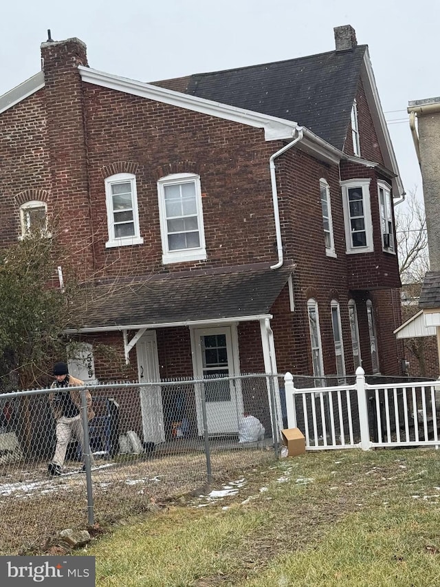 view of front facade featuring fence private yard, brick siding, and a chimney