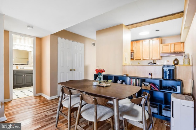 dining room featuring light wood-style flooring, visible vents, and baseboards