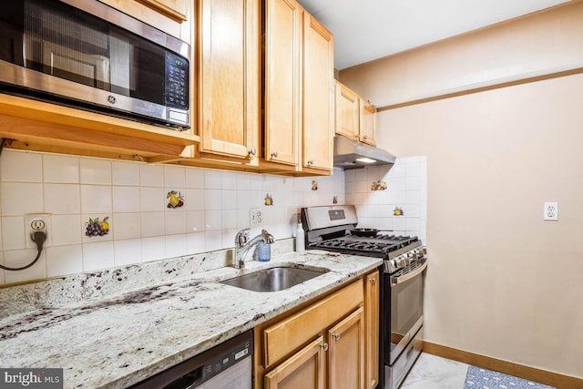 kitchen with stainless steel appliances, decorative backsplash, a sink, under cabinet range hood, and baseboards