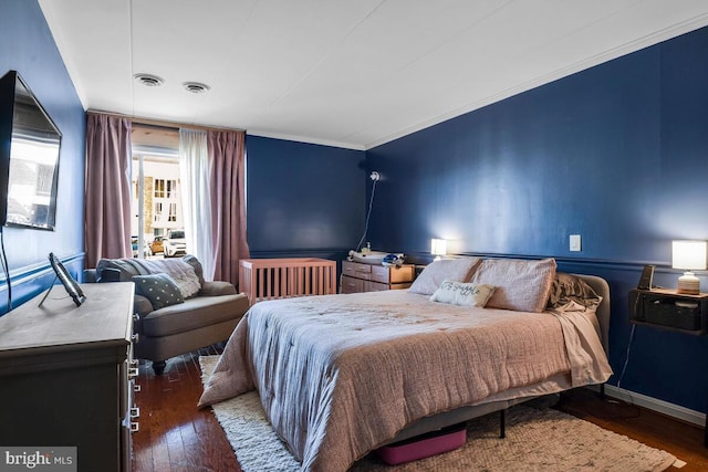 bedroom with radiator, visible vents, ornamental molding, and hardwood / wood-style floors