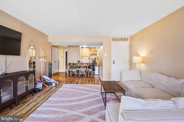 living area featuring visible vents and wood finished floors