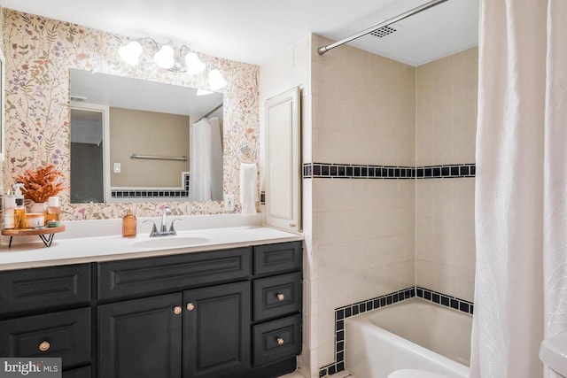 full bath with shower / tub combo, vanity, and wallpapered walls