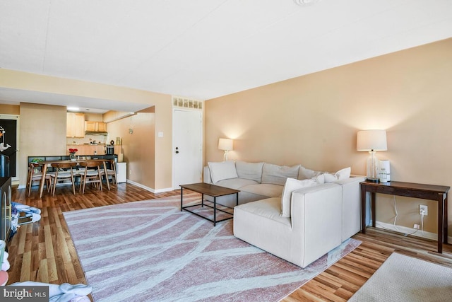 living room featuring wood finished floors, visible vents, and baseboards