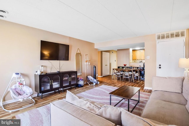 living area featuring wood finished floors, visible vents, and baseboards