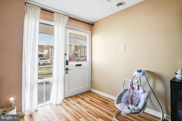 doorway featuring light wood-type flooring, baseboards, and visible vents