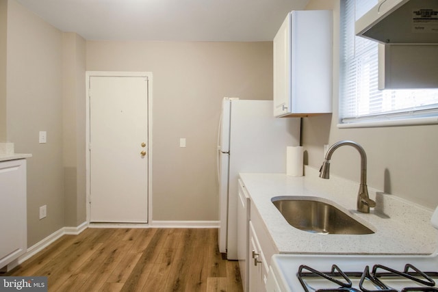 kitchen featuring baseboards, light stone countertops, under cabinet range hood, light wood-style floors, and white cabinetry