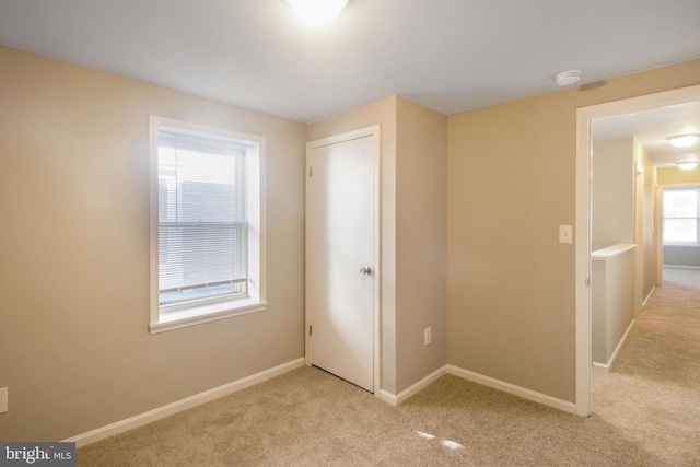 unfurnished bedroom featuring light colored carpet and baseboards