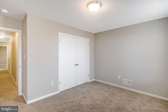 unfurnished bedroom with baseboards, visible vents, a closet, and carpet floors