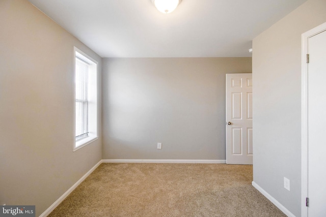 carpeted empty room featuring baseboards