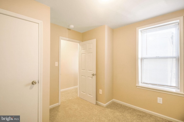 unfurnished bedroom with baseboards and light carpet