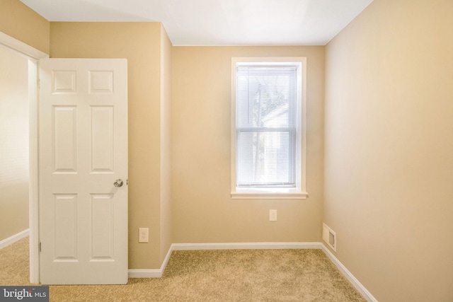 spare room featuring baseboards, visible vents, and light carpet