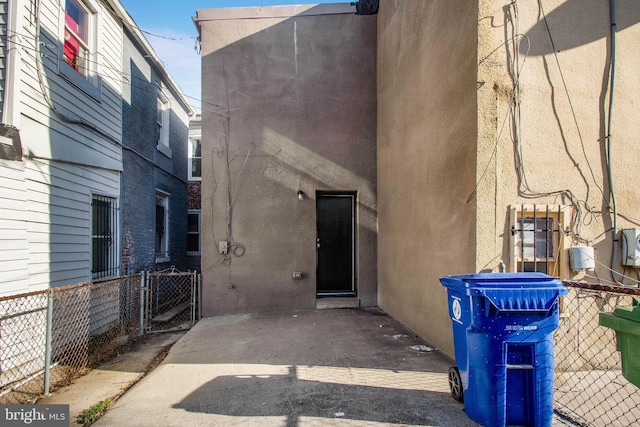 doorway to property featuring a patio area, stucco siding, and fence