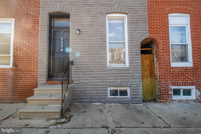 entrance to property featuring brick siding and stone siding