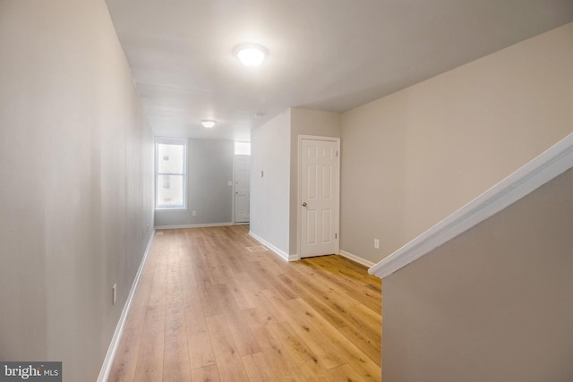 corridor with baseboards and light wood-style floors