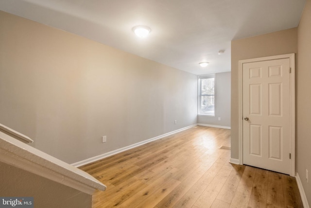 spare room featuring baseboards and light wood-type flooring