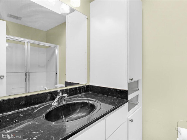 bathroom featuring visible vents, a shower stall, and vanity