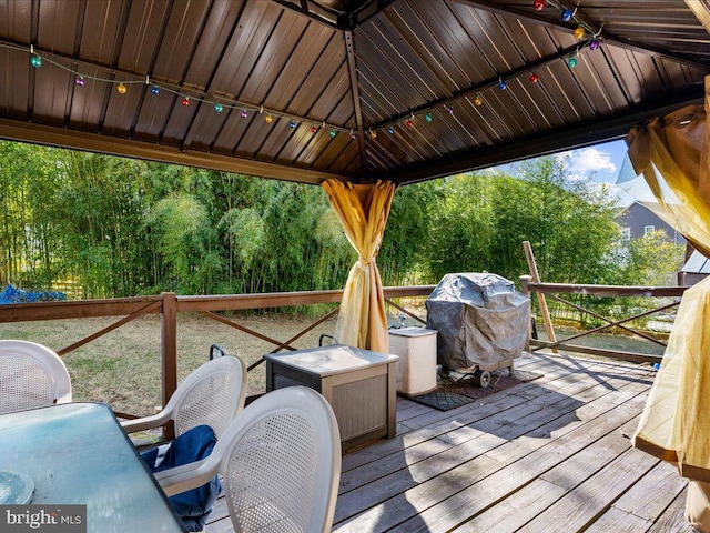 wooden terrace with a gazebo and a grill