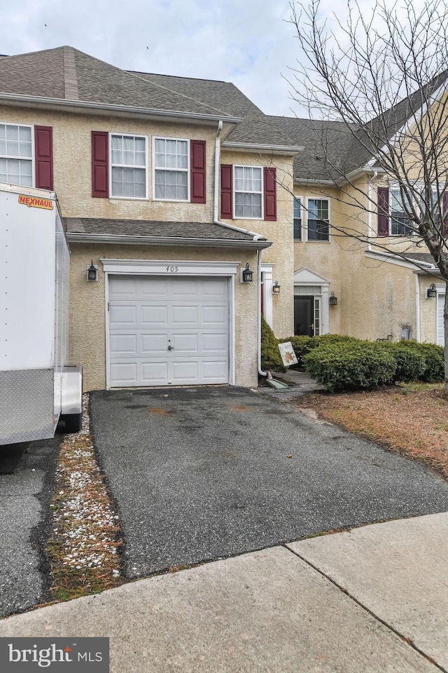 multi unit property with driveway, roof with shingles, an attached garage, and stucco siding