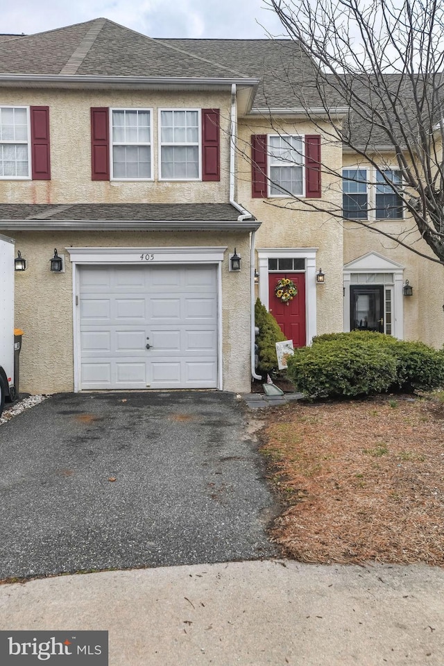 townhome / multi-family property featuring aphalt driveway, roof with shingles, an attached garage, and stucco siding