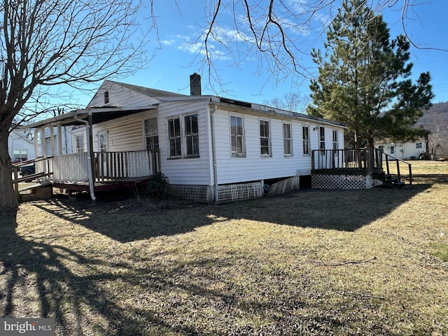 view of home's exterior featuring a chimney, a deck, and a lawn