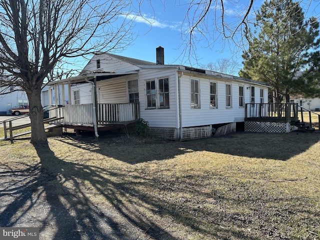 view of home's exterior with a yard, a chimney, crawl space, fence, and a deck