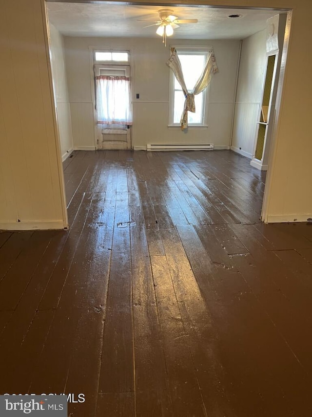 empty room with ceiling fan, dark wood-style flooring, and baseboard heating