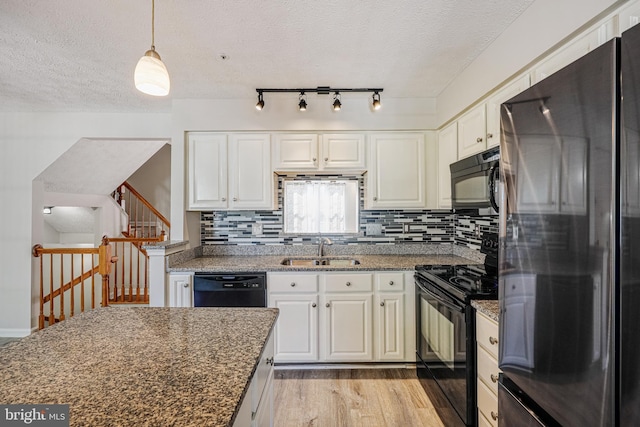 kitchen featuring black appliances, white cabinets, light wood-type flooring, and a sink