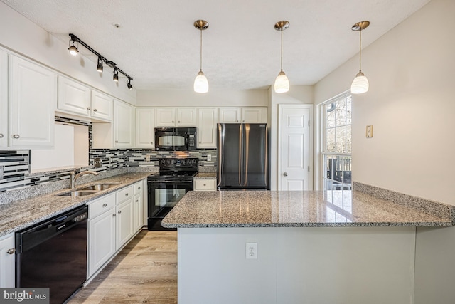 kitchen featuring black appliances, decorative backsplash, a peninsula, white cabinetry, and a sink