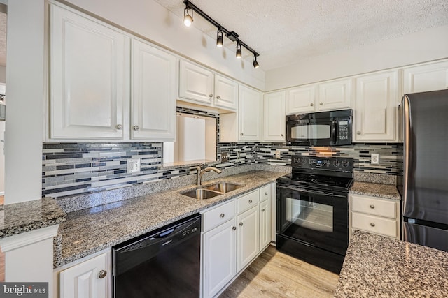 kitchen with light wood-style flooring, white cabinets, black appliances, and a sink