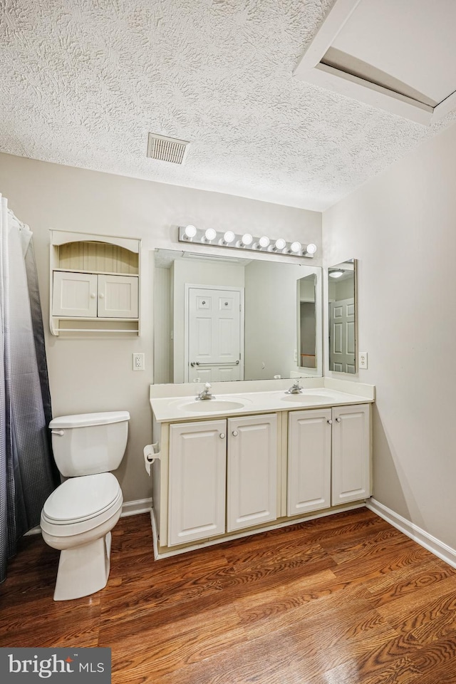 full bath featuring toilet, wood finished floors, and a sink