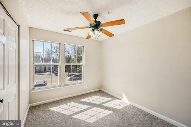 empty room with visible vents, carpet, baseboards, and a textured ceiling