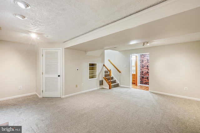 finished basement with a textured ceiling, stairway, baseboards, and light carpet