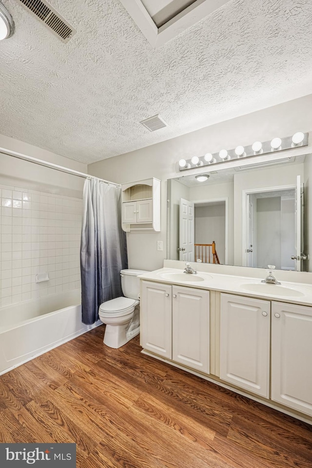 bathroom with visible vents, toilet, wood finished floors, and a sink