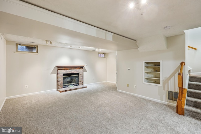 finished basement featuring built in shelves, baseboards, carpet floors, a fireplace, and stairs