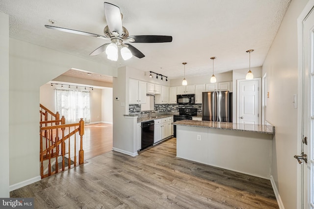 kitchen featuring wood finished floors, a peninsula, decorative backsplash, black appliances, and white cabinetry