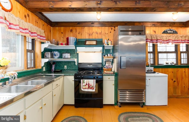 kitchen featuring built in fridge, wood walls, white cabinets, open shelves, and black gas range oven