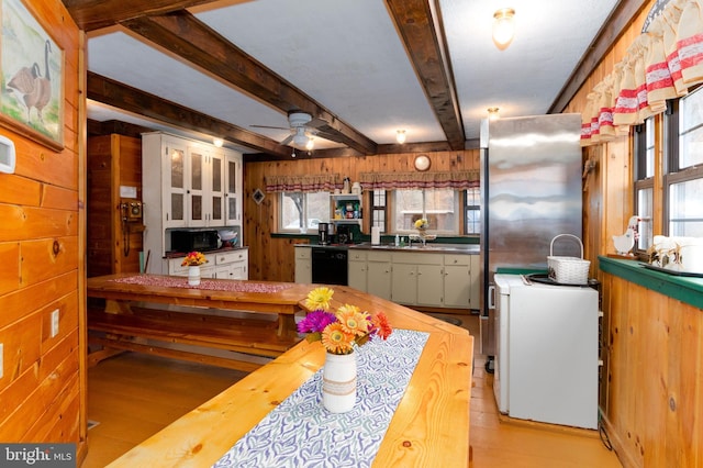 kitchen with light wood finished floors, wooden walls, dishwasher, butcher block countertops, and beam ceiling