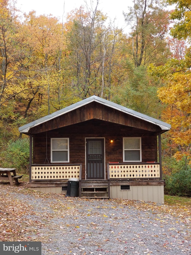 view of front of home featuring crawl space, a porch, and a wooded view