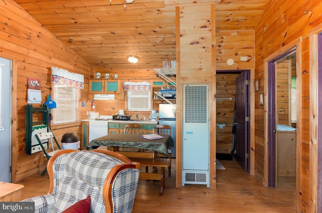 interior space with lofted ceiling, freestanding refrigerator, wood ceiling, wood walls, and wood finished floors