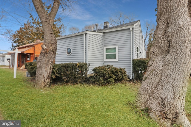 view of side of property featuring a lawn and a chimney