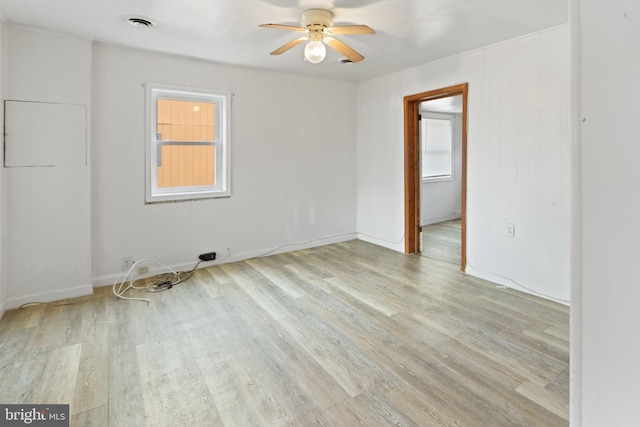 spare room with a ceiling fan, visible vents, baseboards, and wood finished floors