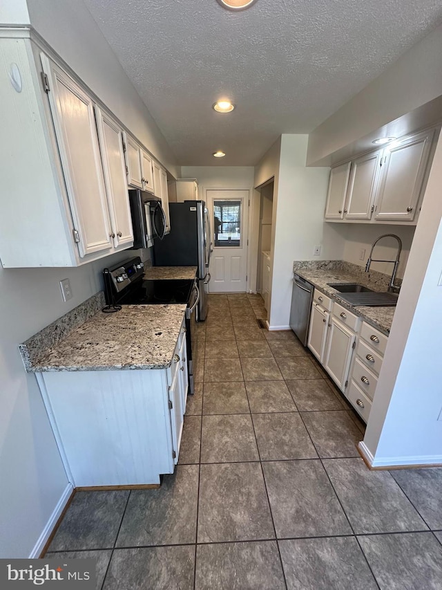 kitchen with black microwave, dishwasher, electric range oven, white cabinets, and a sink