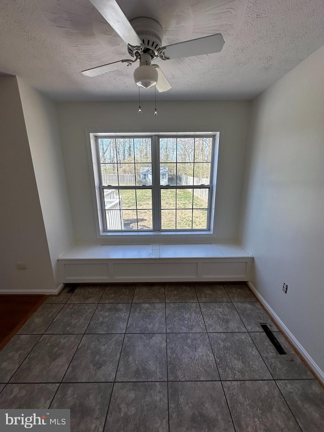 empty room featuring a wealth of natural light, baseboards, and a textured ceiling