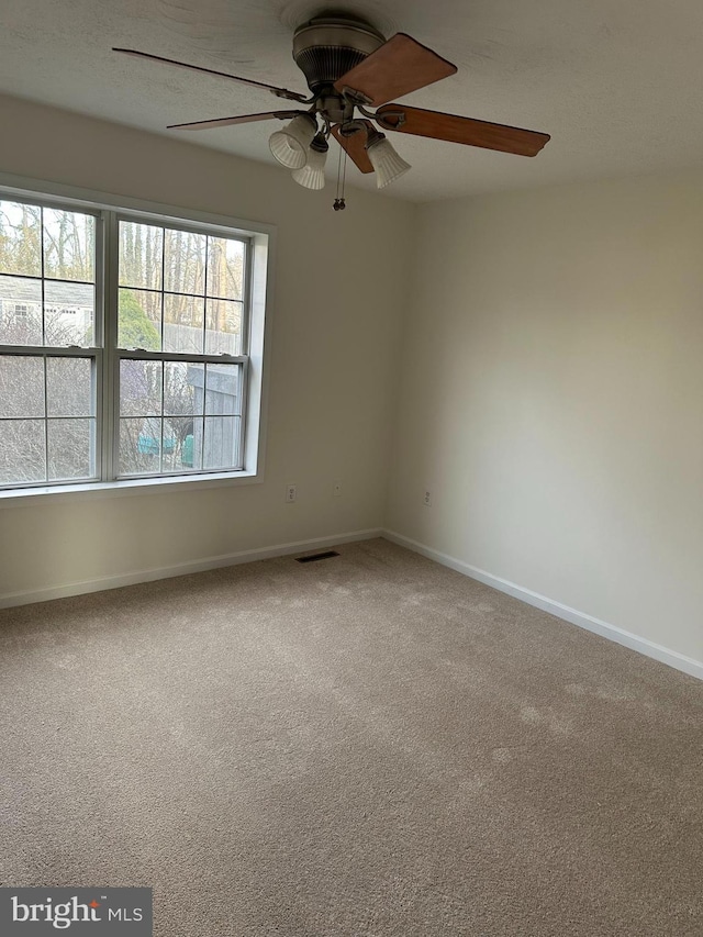 carpeted spare room with a ceiling fan, baseboards, and visible vents