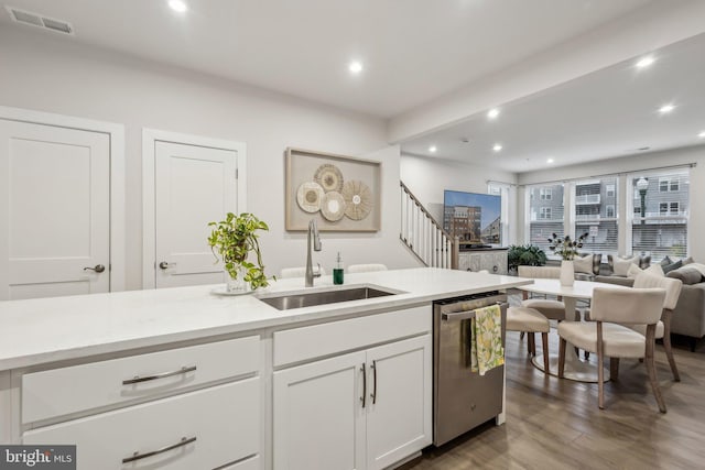 kitchen with a sink, visible vents, white cabinetry, light countertops, and stainless steel dishwasher