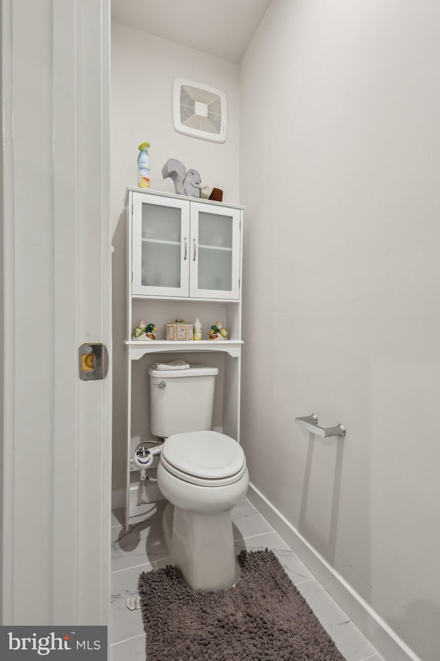 bathroom featuring marble finish floor, toilet, and baseboards