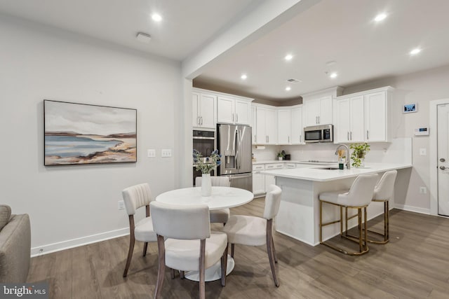 kitchen featuring appliances with stainless steel finishes, white cabinets, a peninsula, and wood finished floors