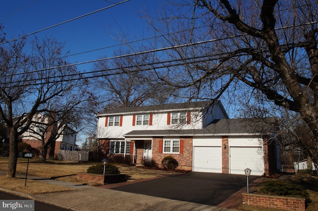 traditional home featuring aphalt driveway, an attached garage, brick siding, and fence